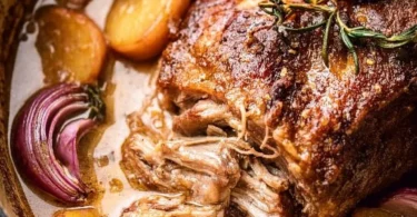 Apple cider braised pork shoulder served with vegetables and herbs