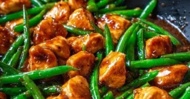 Grilled chicken breast served with sautéed green beans on a white plate