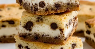 Delicious chocolate chip cheesecake bars on a plate with chocolate chips nearby