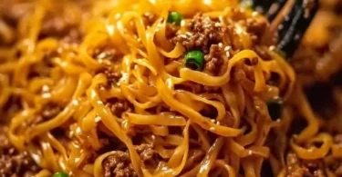 Bowl of delicious Mongolian ground beef noodles garnished with green onions.