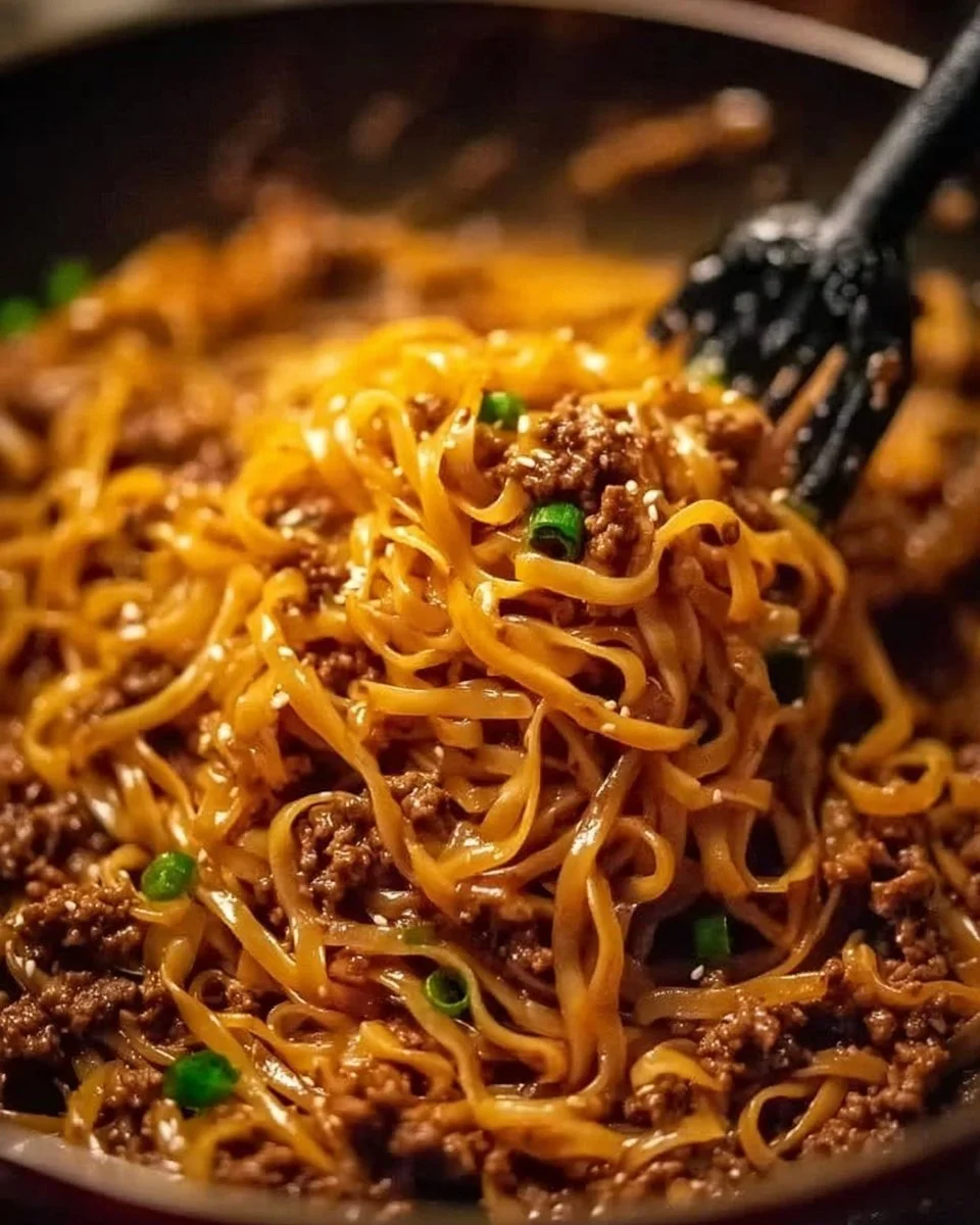 Bowl of delicious Mongolian ground beef noodles garnished with green onions.