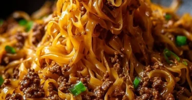 Mongolian ground beef noodles garnished with fresh vegetables and herbs