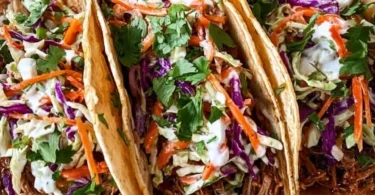 Delicious pulled pork tacos topped with tangy slaw served on a plate